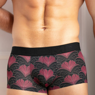 Man wearing a black and red patterned underwear against a neutral background